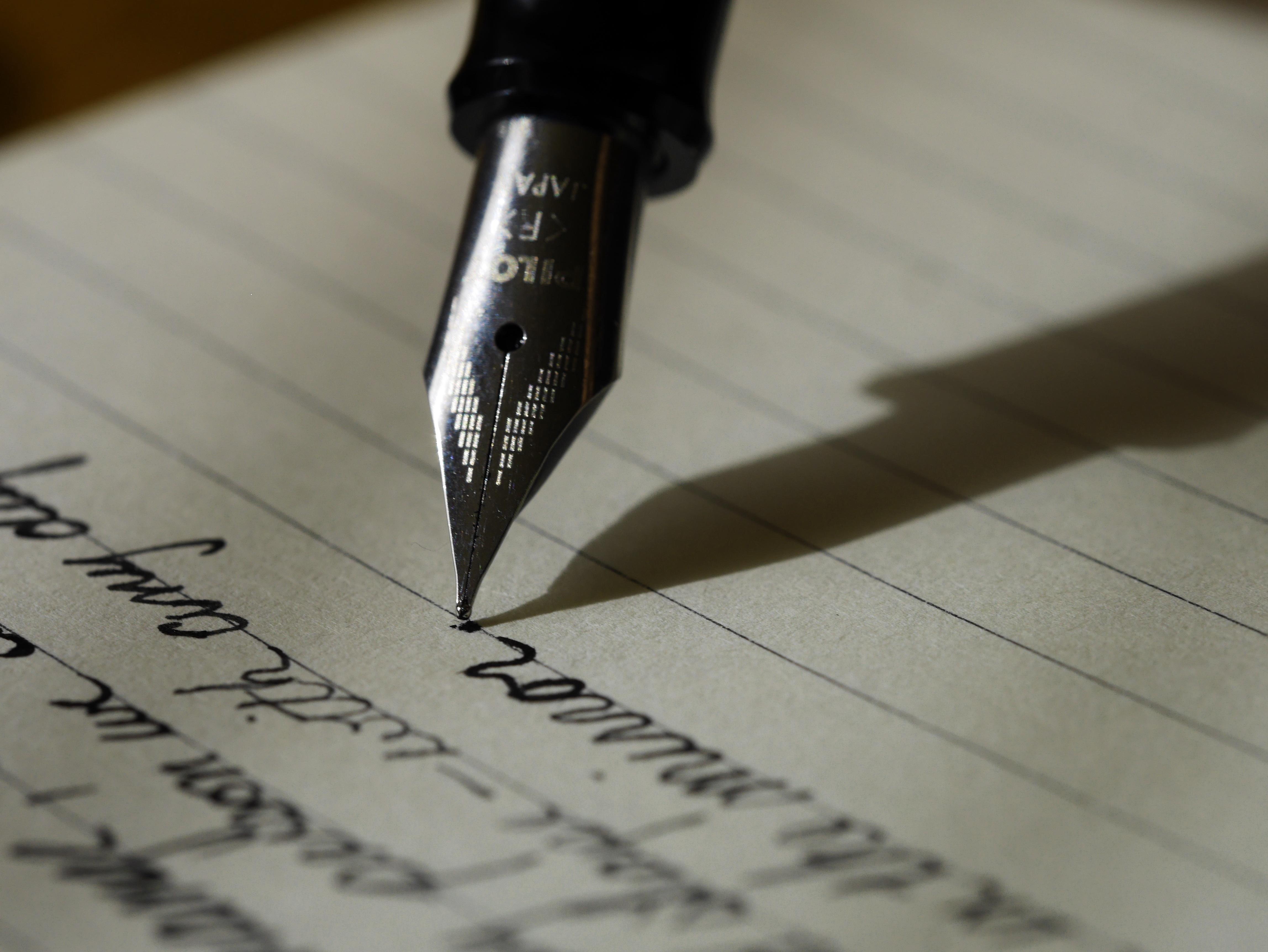 A photograph of a fountain pen writing on lined paper. By Arron Burden via Unsplash.